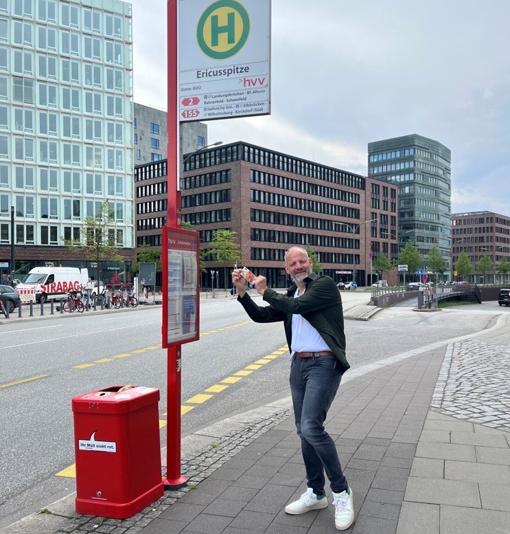 Jörg Bantelmann von LPJ steht an der Bushaltestelle und freut sich auf das 9-Euro Ticket.